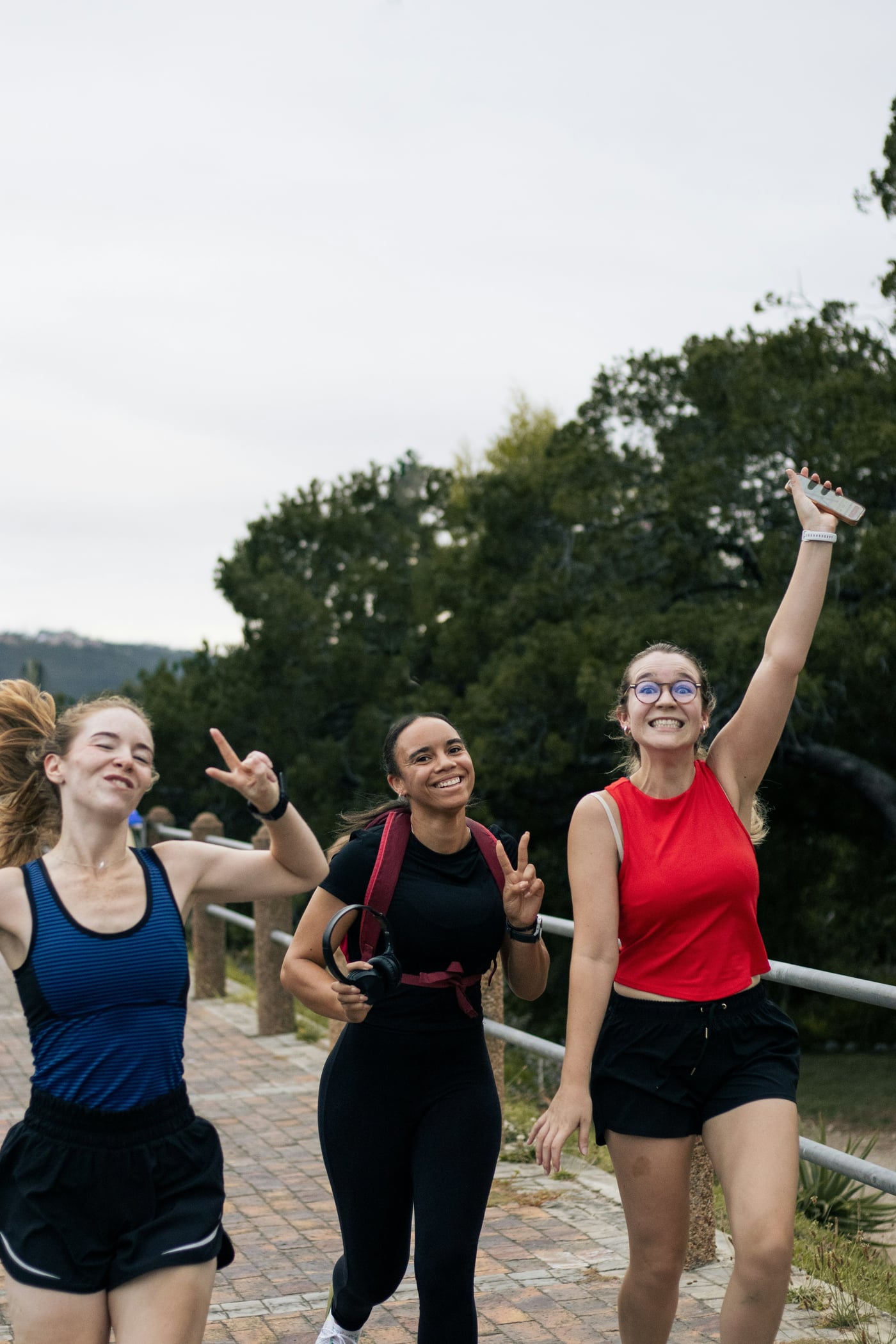 Three friends running together, arms up and laughing